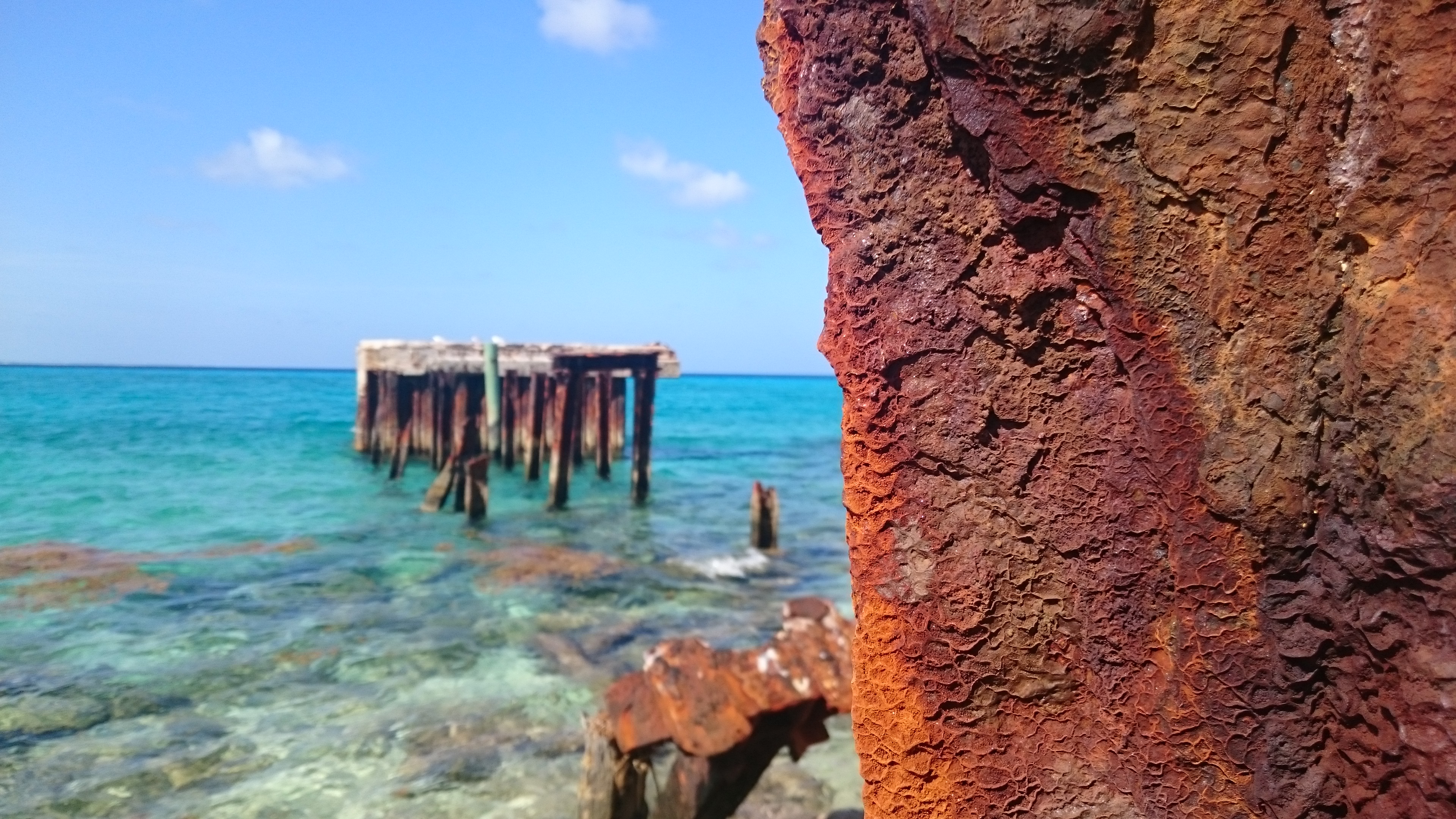 a rusting piece of metal with the ocean in the background